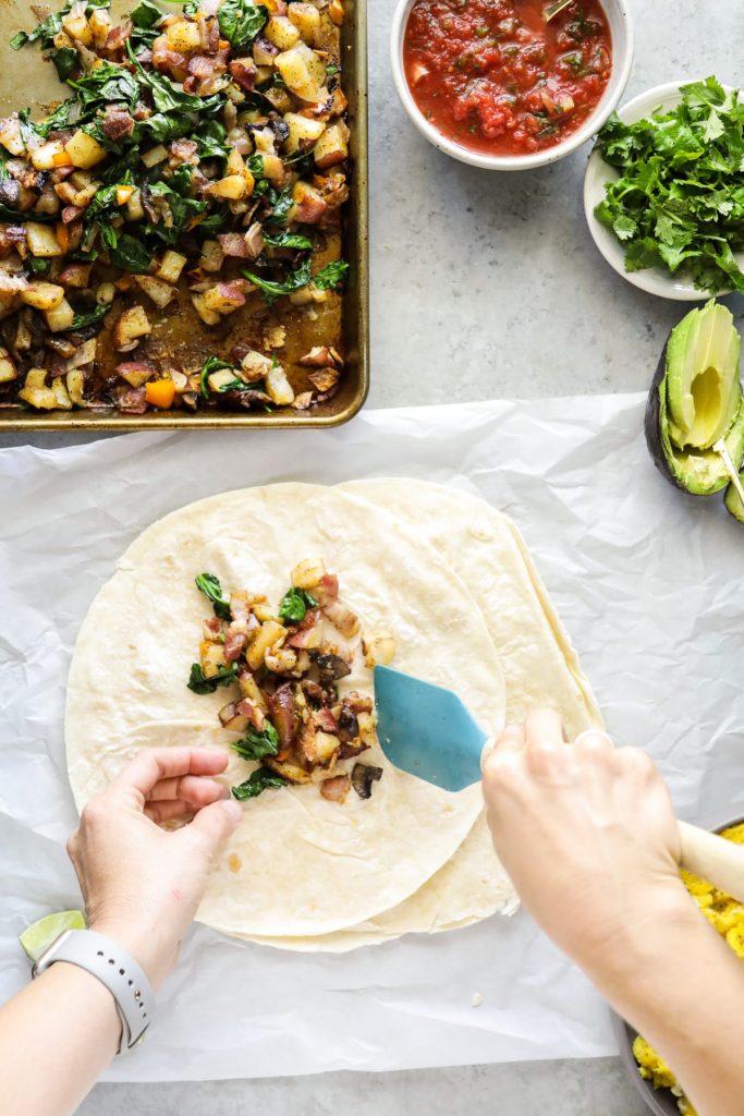 Sheet pan veggies and bacon, eggs, cilantro, avocado, and salsa come together in these loaded breakfast-style burritos. So flavorful and easy! Vegetarian option, too.