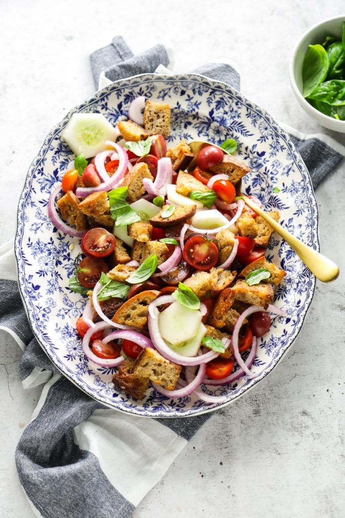 A classic summer panzanella salad made with homemade croutons, grape or cherry tomatoes, cucumbers, red onions, and fresh basil.