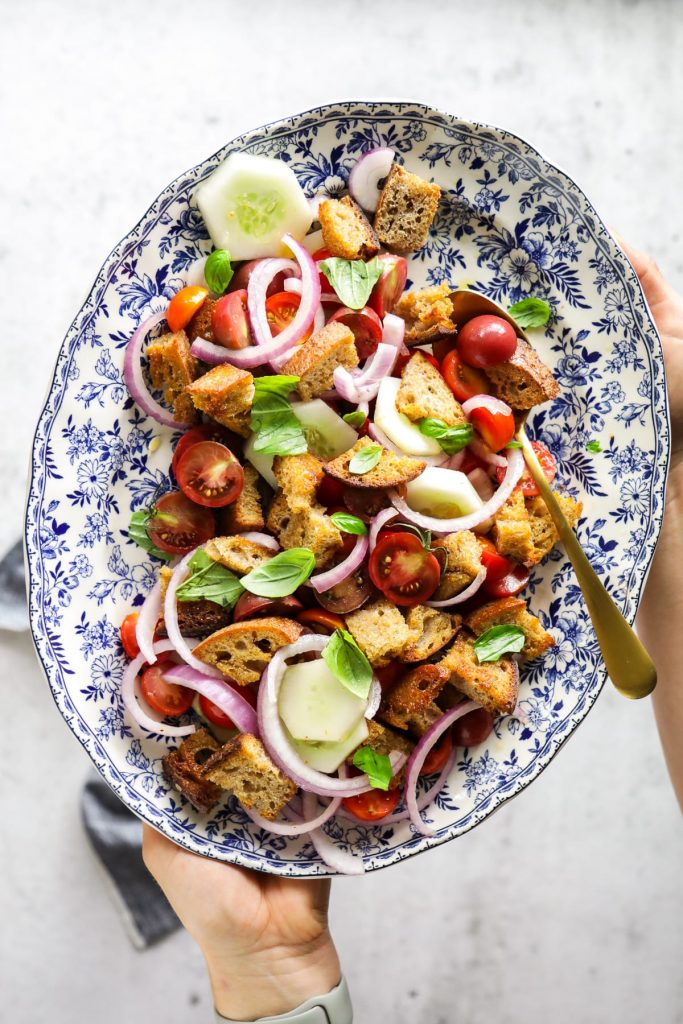 A classic summer panzanella salad made with homemade croutons, grape or cherry tomatoes, cucumbers, red onions, and fresh basil.