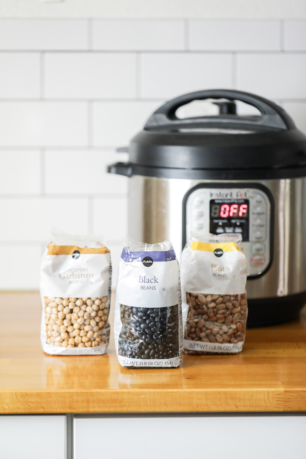 Different types of beans: black beans, chickpeas, and pinto beans on a counter next to an Instant Pot.