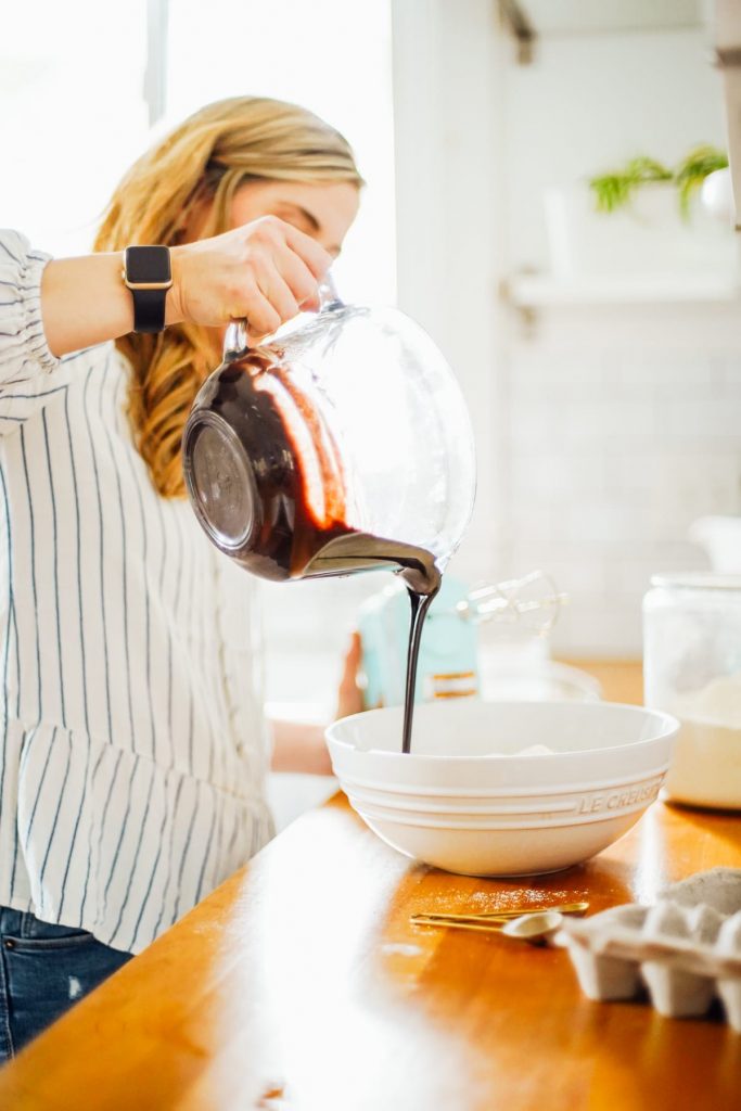 Adding chocolate mixture (butter and cocoa powder) to cake batter