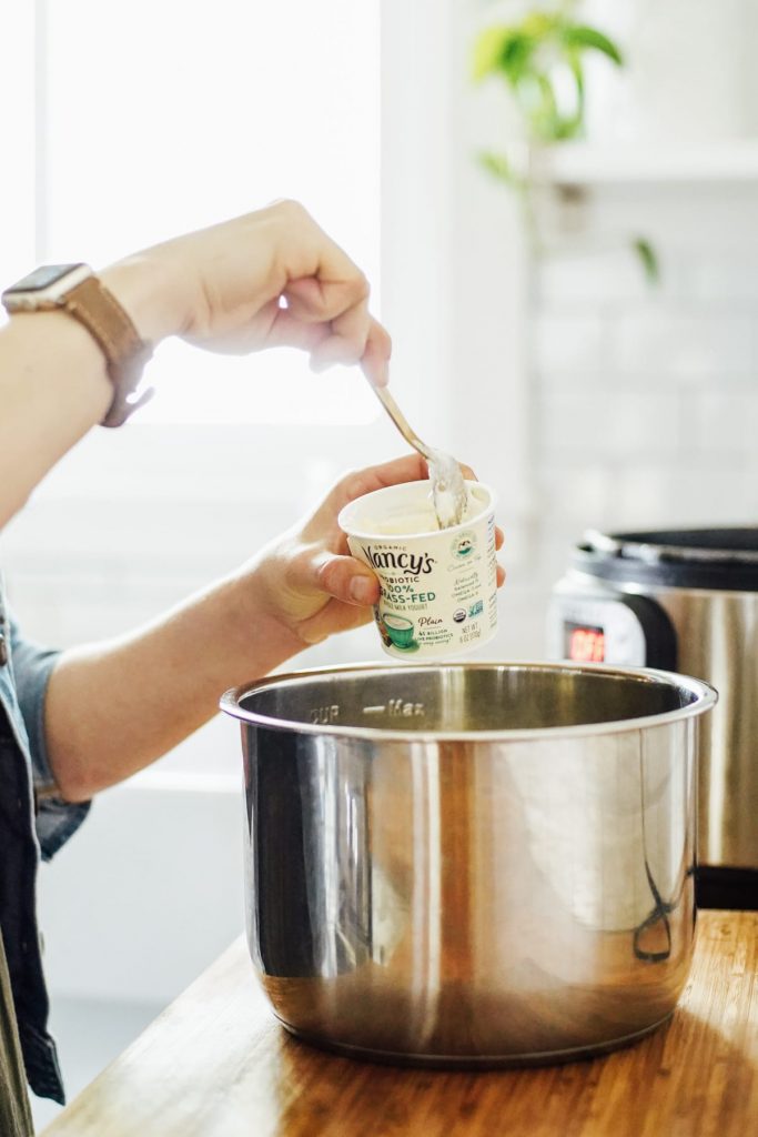 Scooping the yogurt starter into the milk to make homemade yogurt