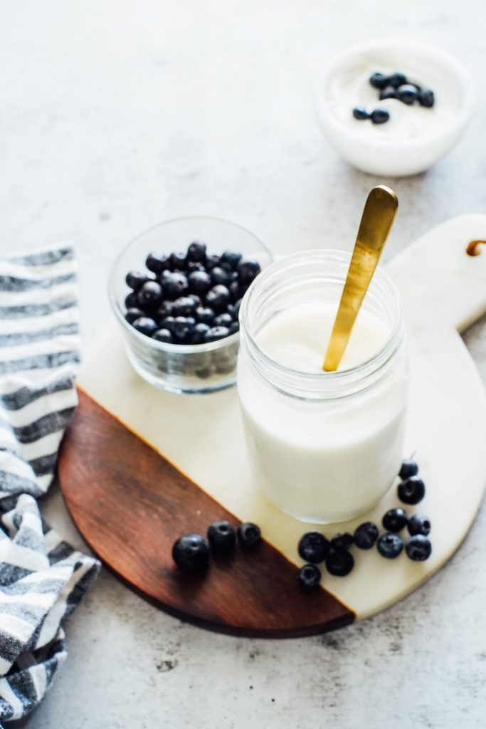 Homemade yogurt in a storage jar served with fruit