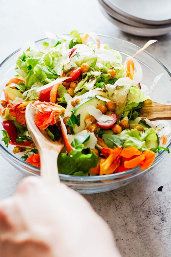 tossing salad ingredients together