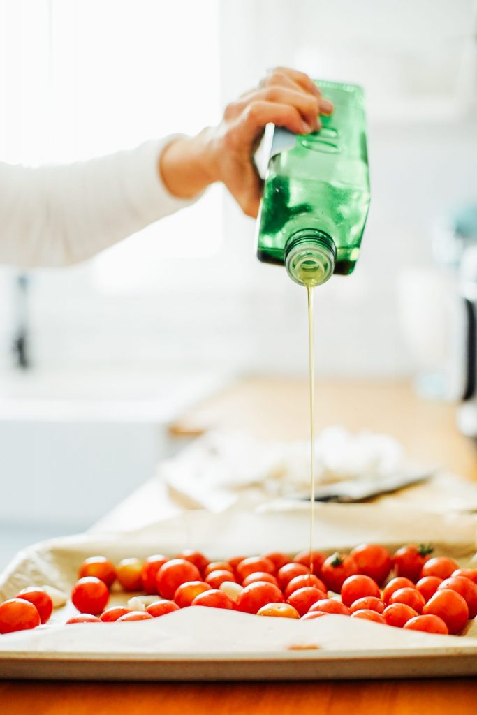 drizzling olive oil over tomatoes to roast