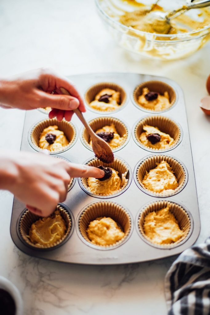 einkorn muffin batter with cinnamon swirl mixture spooned on top 