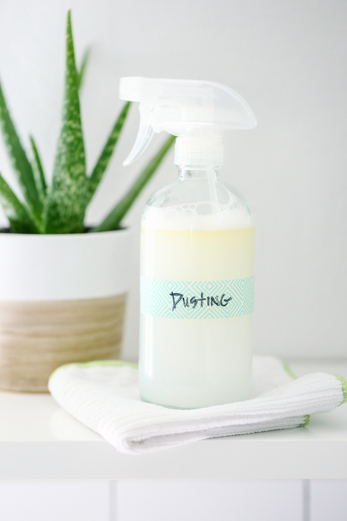 Dusting spray made with castile soap in a glass spray bottle with a turquoise label.
