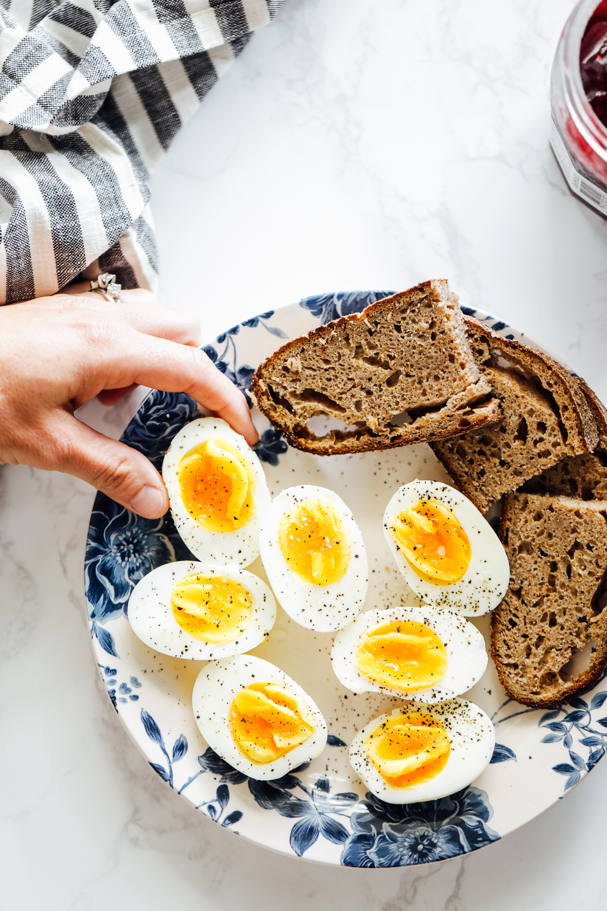 Hard boiled eggs cut in half on a blue and white plate with sourdough bread slices.
