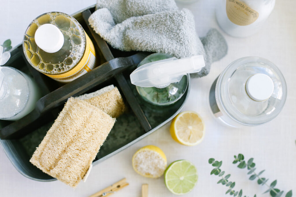 natural cleaners in a basket: all-purpose spray bottle, vinegar, castile soap, lemons, and a sponge.
