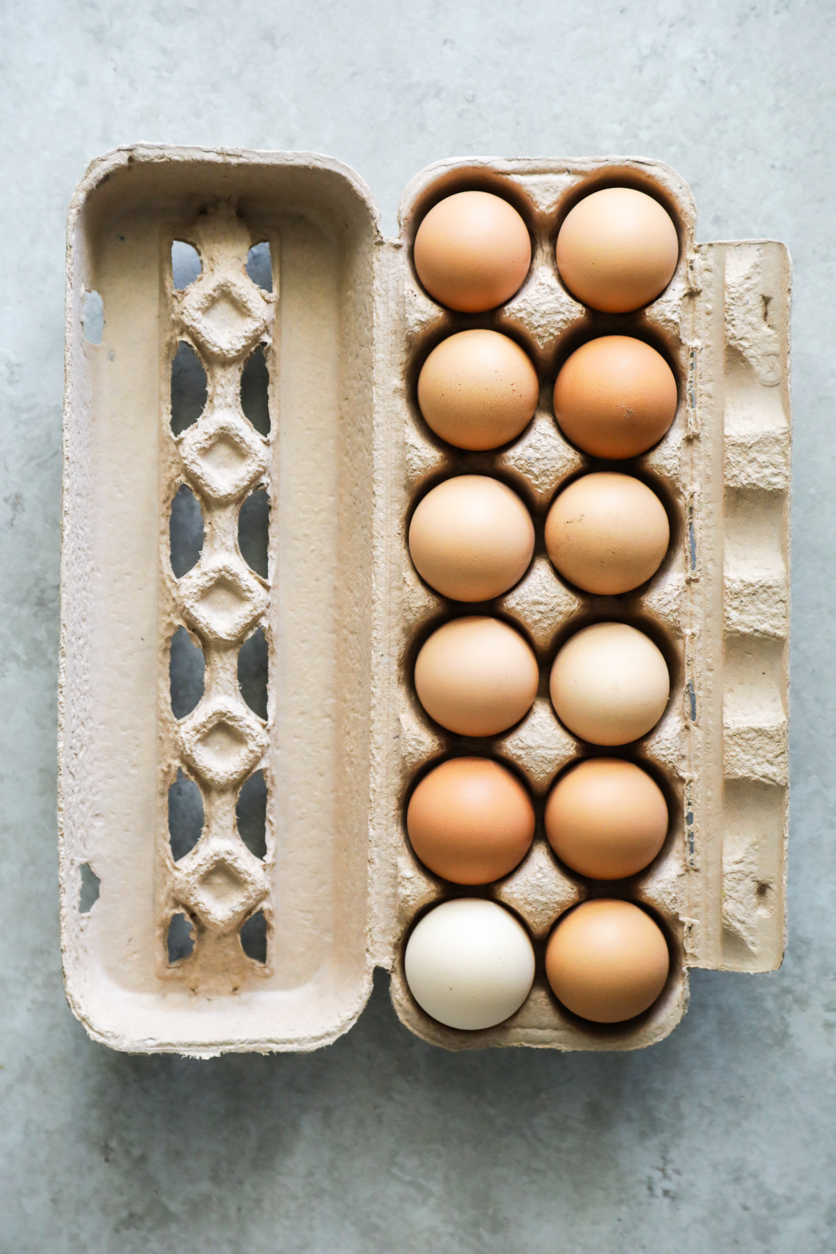 White and brown eggs in a brown egg carton.