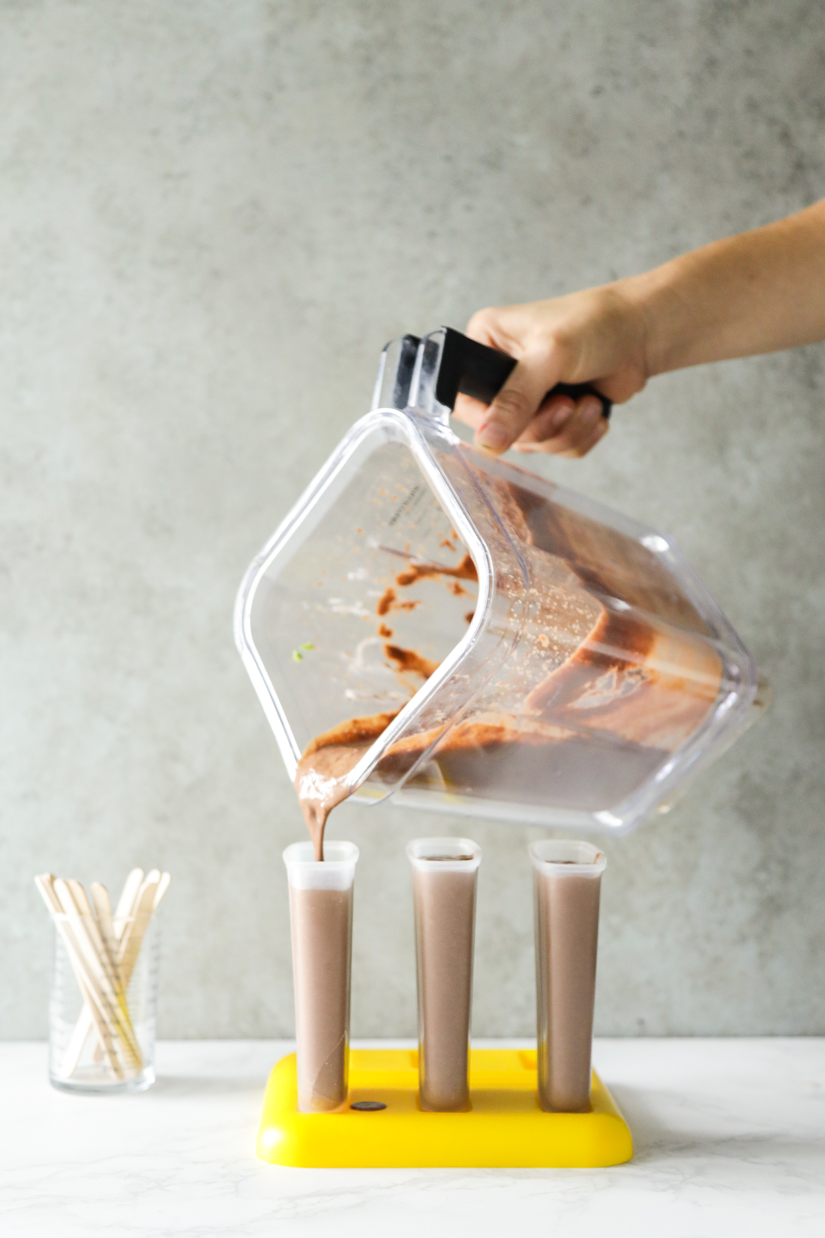 Pouring fudge popsicle ingredients into a plastic popsicle mold.