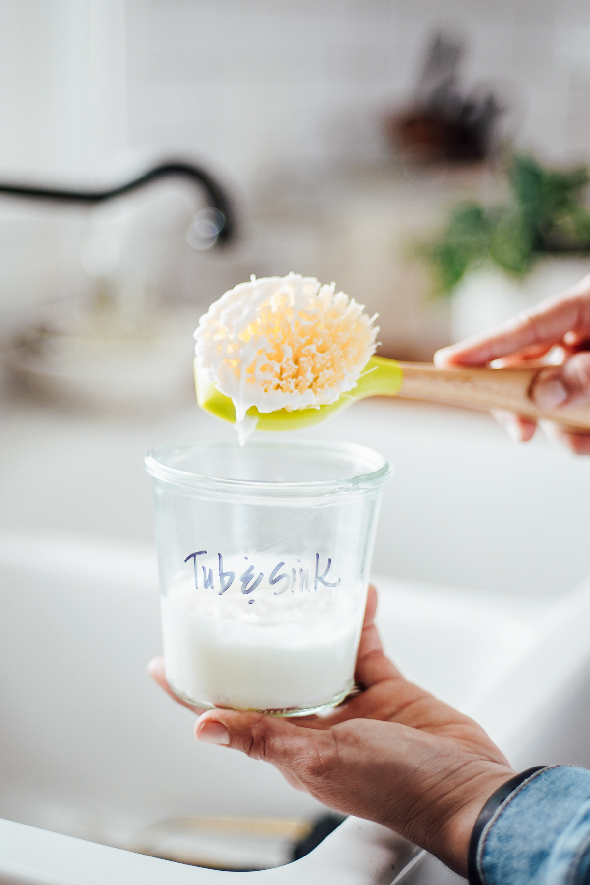 Tub and sink scrub cleaner made with castile soap in a glass container over the sink.