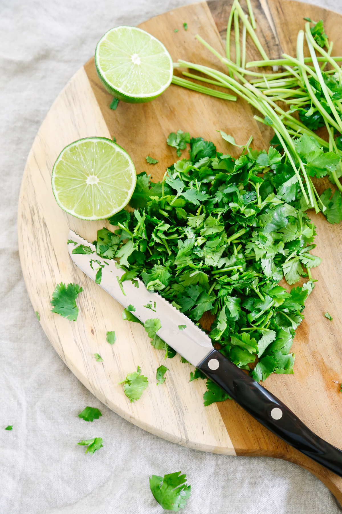Chopped cilantro on a cutting board with a knife and halved lime.