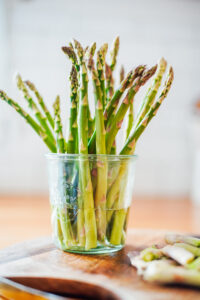 Asparagus sitting upright in a glass jar with 1 inch of water at the bottom.