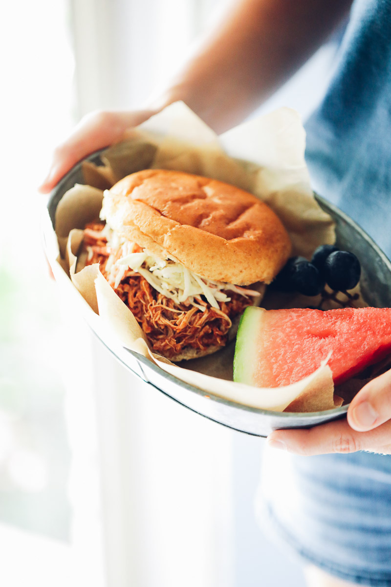 BBQ pulled chicken in a brioche bun topped with coleslaw with watermelon on the side.