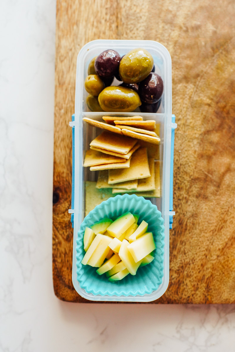 Olives, crackers, and cheese in a plastic snack container.