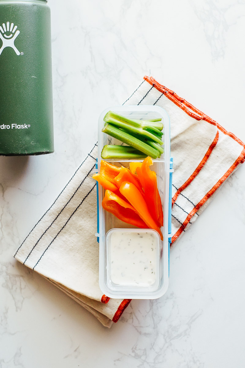 Veggies with homemade ranch dip in a plastic snack container.
