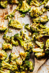 Roasted broccoli on a sheet pan on a kitchen counter.