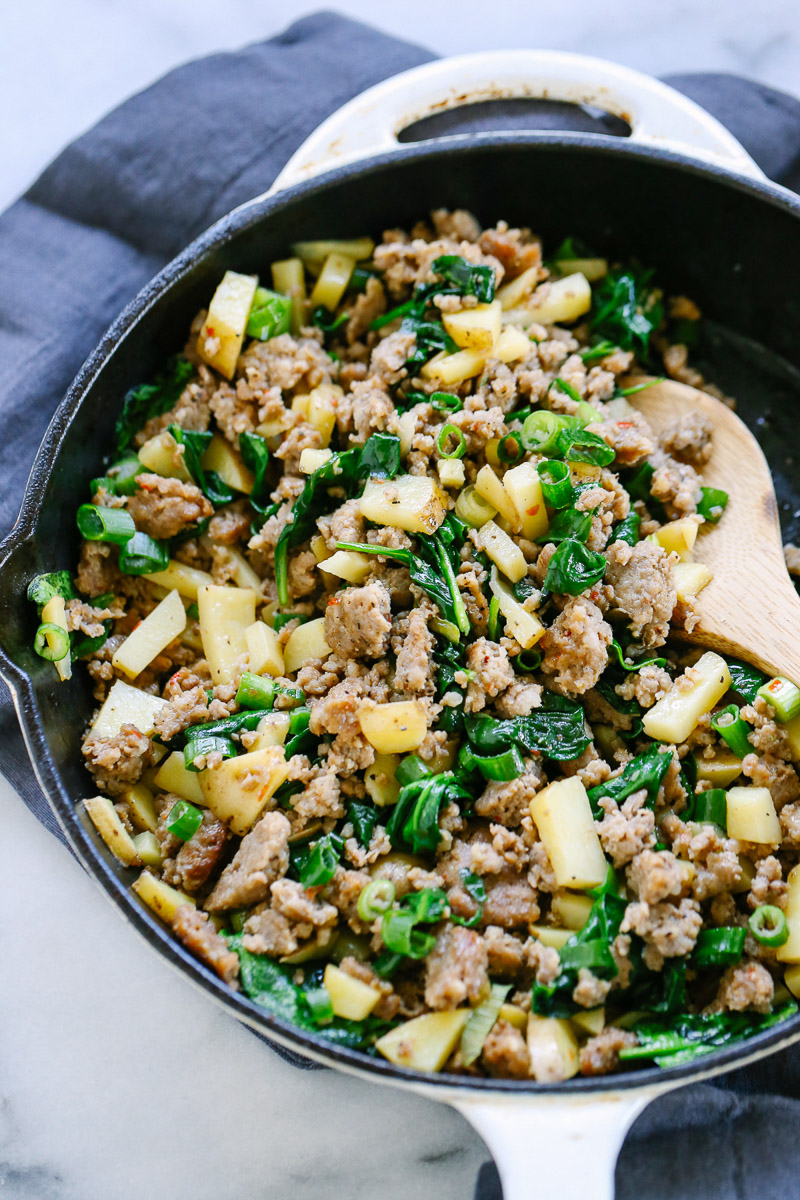 Sausage and potato hash in a white cast iron skillet.