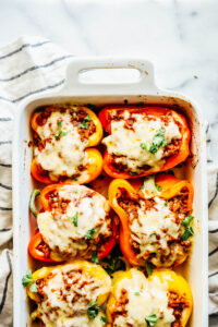 Melted cheese over the stuffed bell peppers in a baking dish.