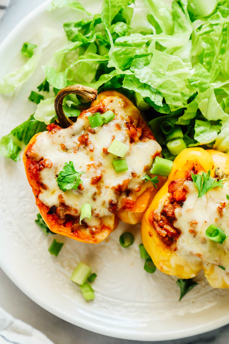 Stuffed bell peppers on a plate with salad.