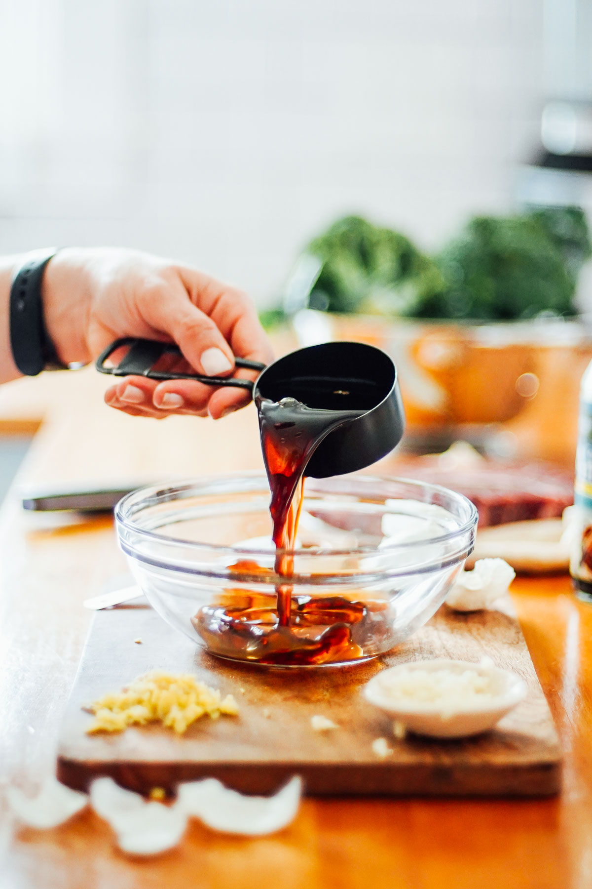 Pouring soy sauce from a measuring cup into a large bowl. 