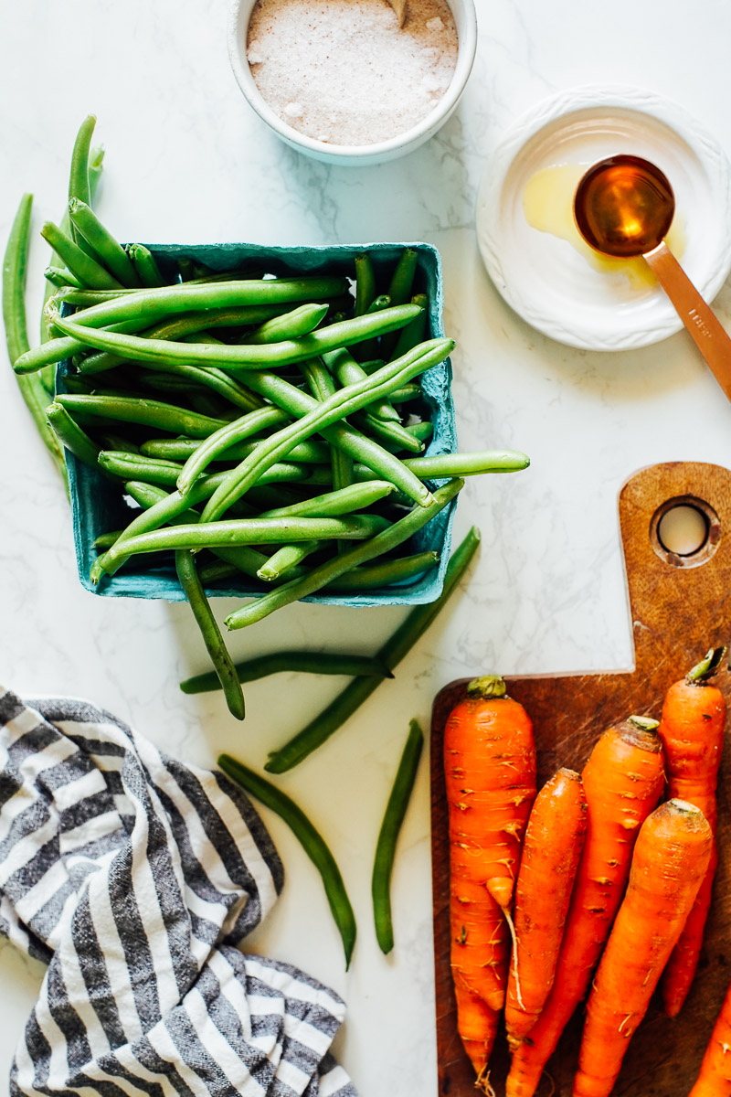 Green beans and carrots on a counter top, ready to be cut and trimmed.