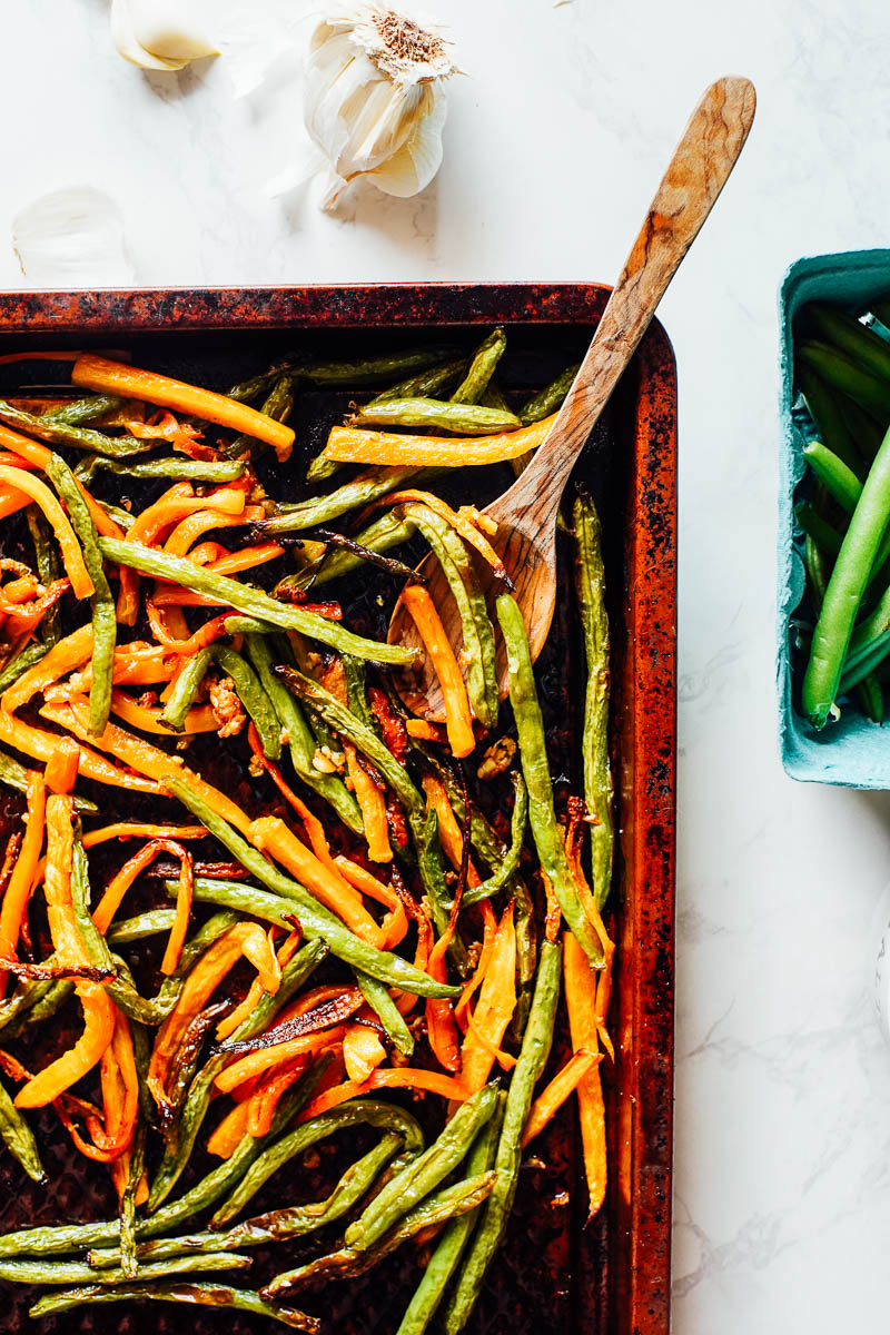 Roasted green beans and carrots on a sheet pan after removing from the oven.