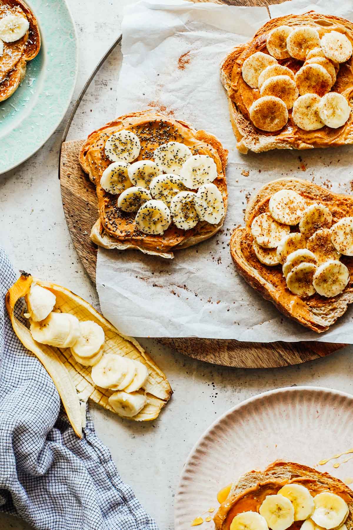 5 different banana toasts with peanut butter on a cutting board.