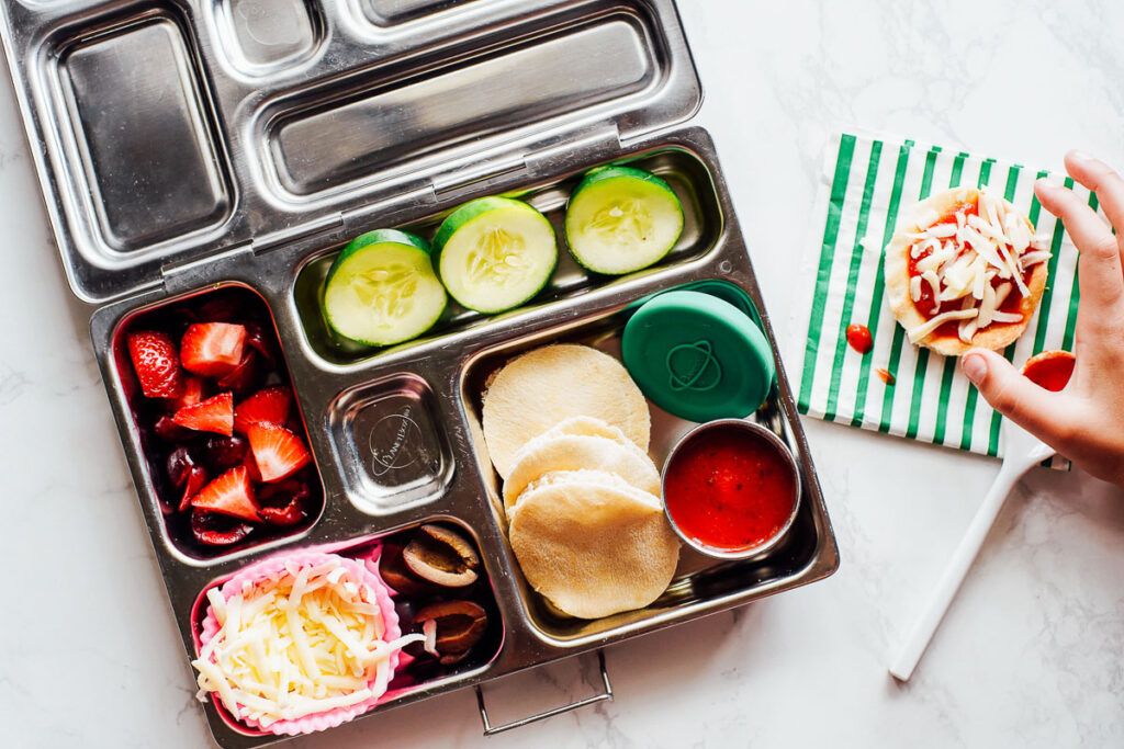 Homemade pizza lunchable with strawberries and cucumbers.