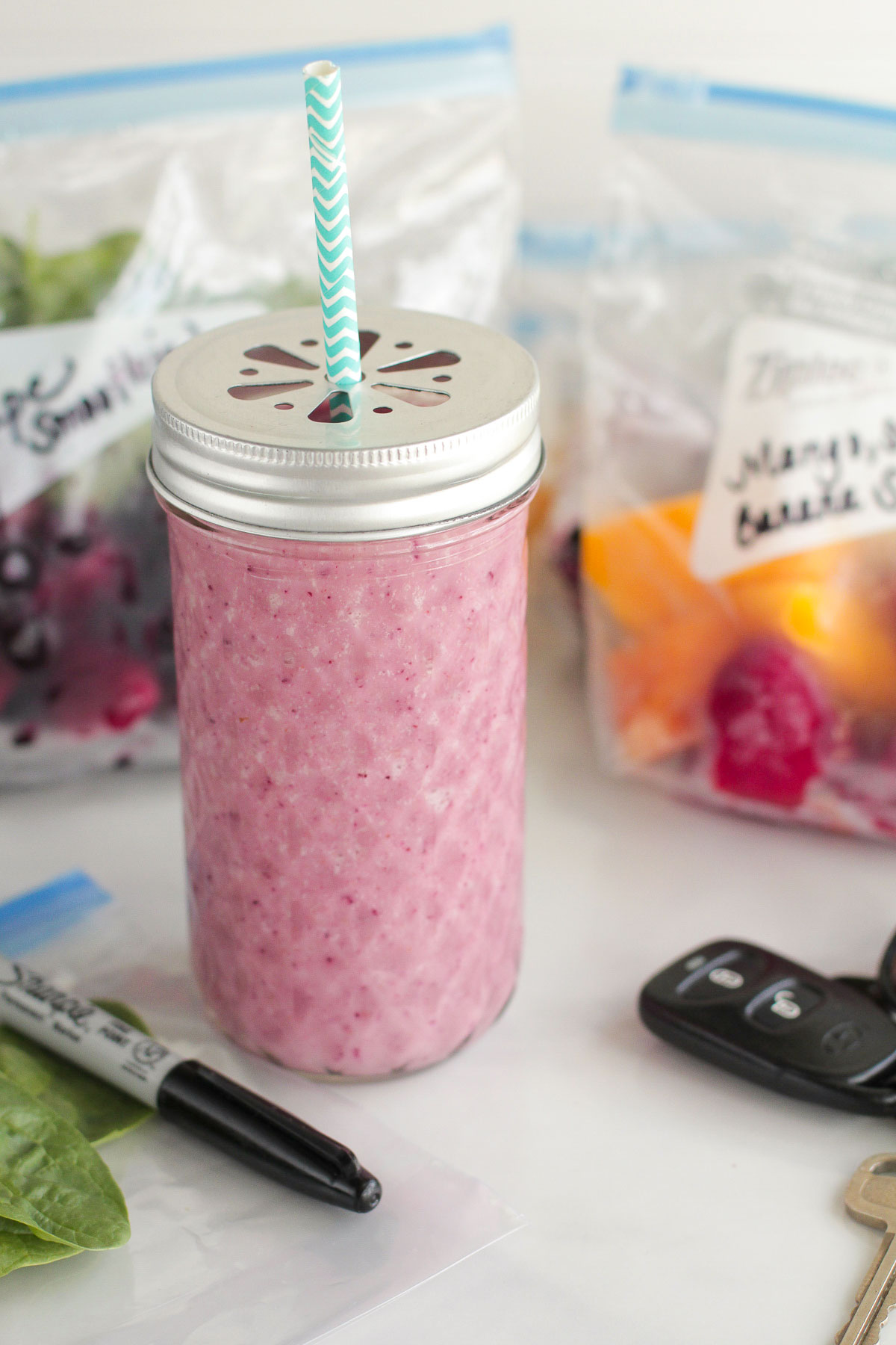 Strawberry Mango Smoothie in a tall glass mason jar with a blue stripped straw.