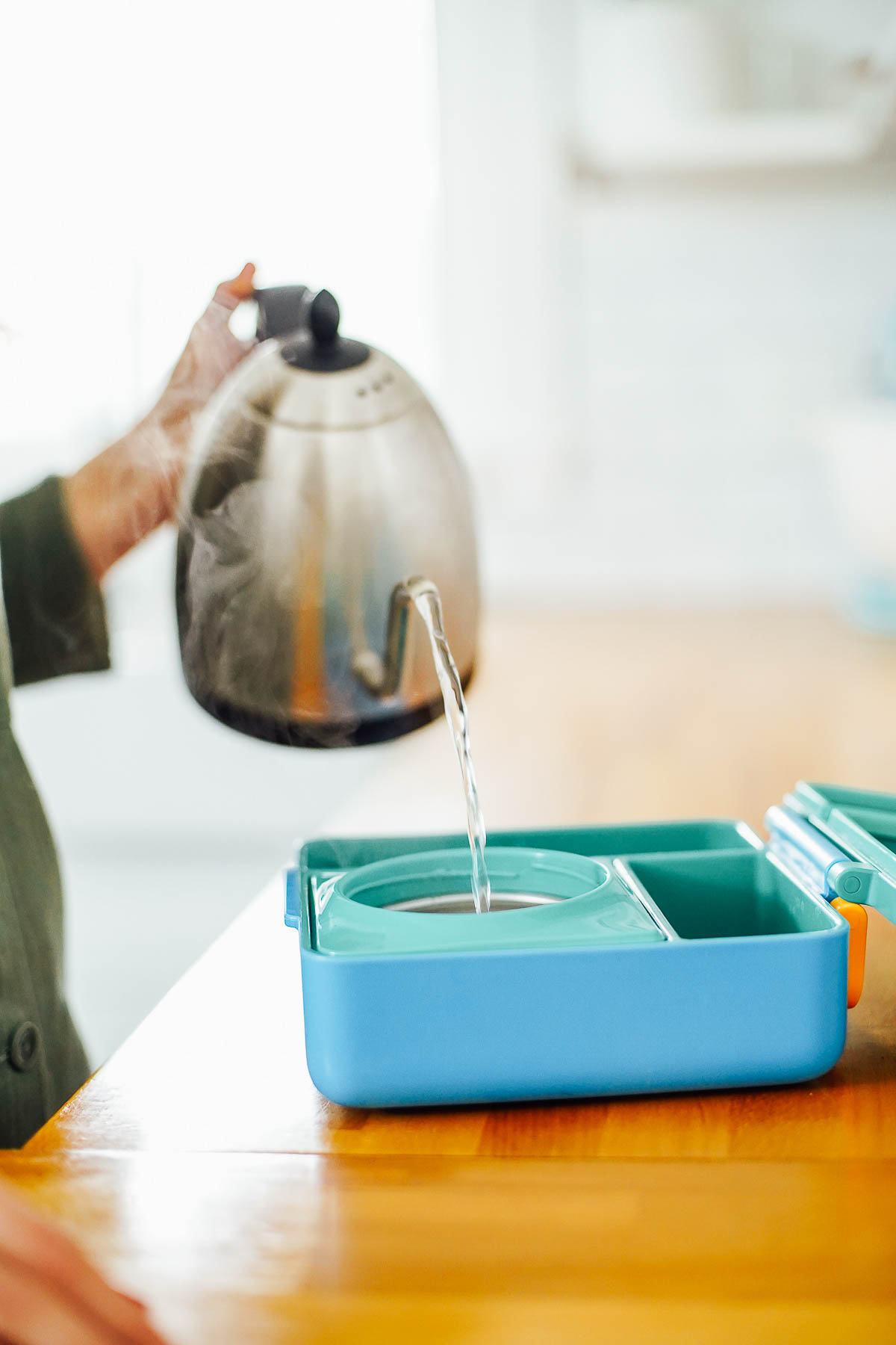 Pouring hot water from a kettle into a thermos.
