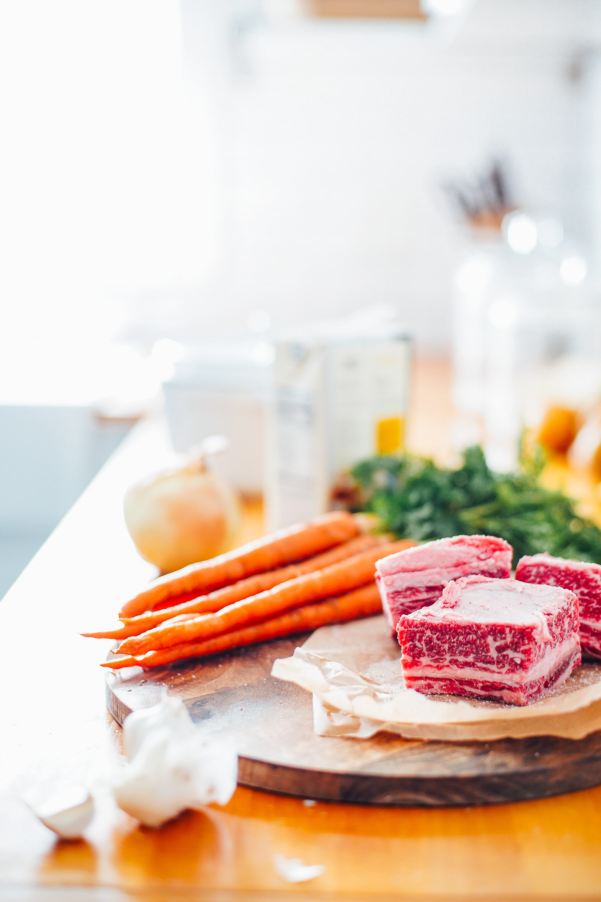 Ingredients on a countertop: carrots, short ribs, and garlic. 