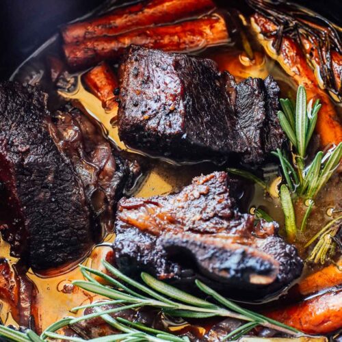 Short ribs in a dutch oven with carrots and rosemary.