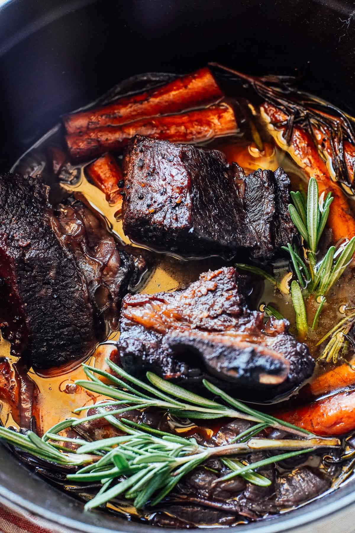 Short ribs in a dutch oven with carrots and rosemary. 