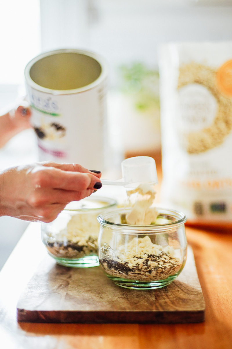 Adding protein powder to the oats and chia seeds in a glass jar.