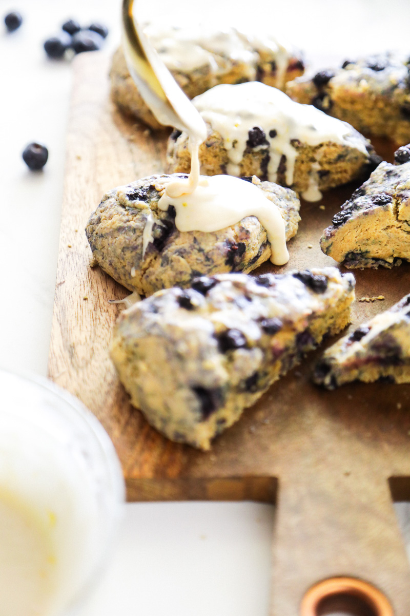 Blueberry scones on a cutting board with drizzle glaze on top.