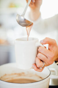 Pouring hot cocoa into a white mug.