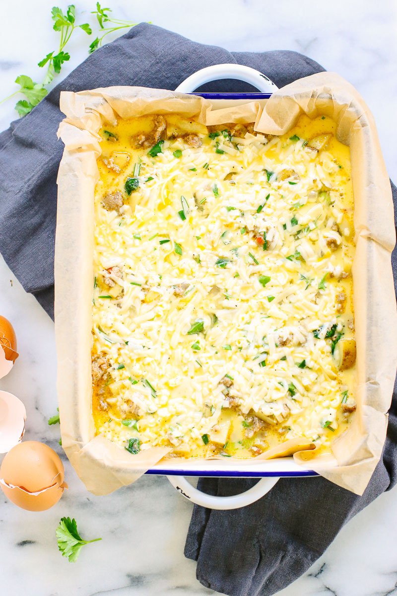 Uncooked eggs mixed with sausage and potatoes in a casserole dish.