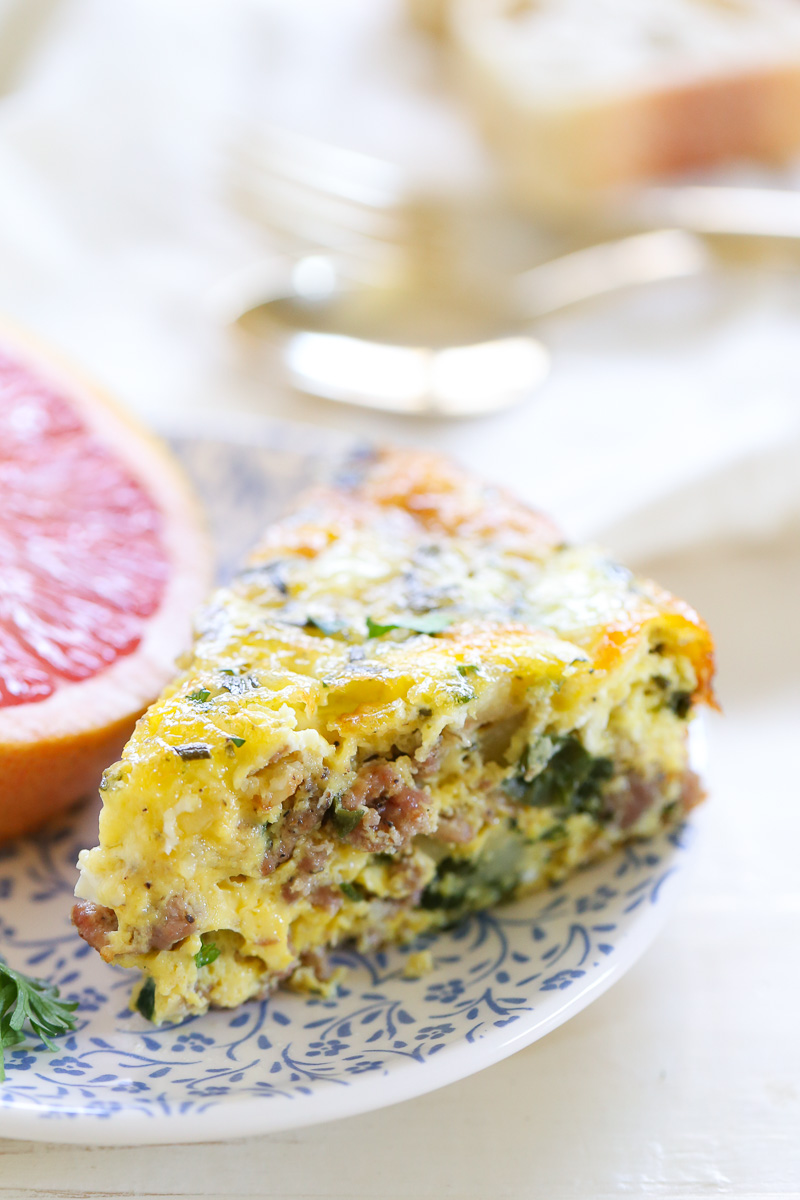 A slice of egg casserole on a blue and white plate with a grapefruit.