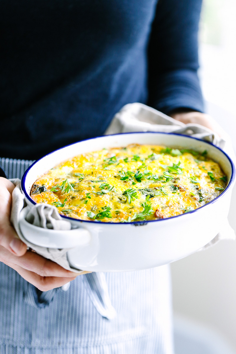 Holding the cooked egg breakfast casserole dish with two towels.