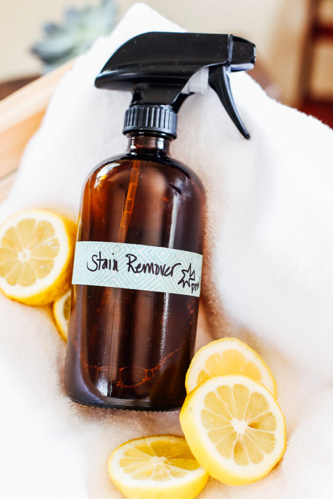 Homemade stain remover bottle surrounded by lemon slices.