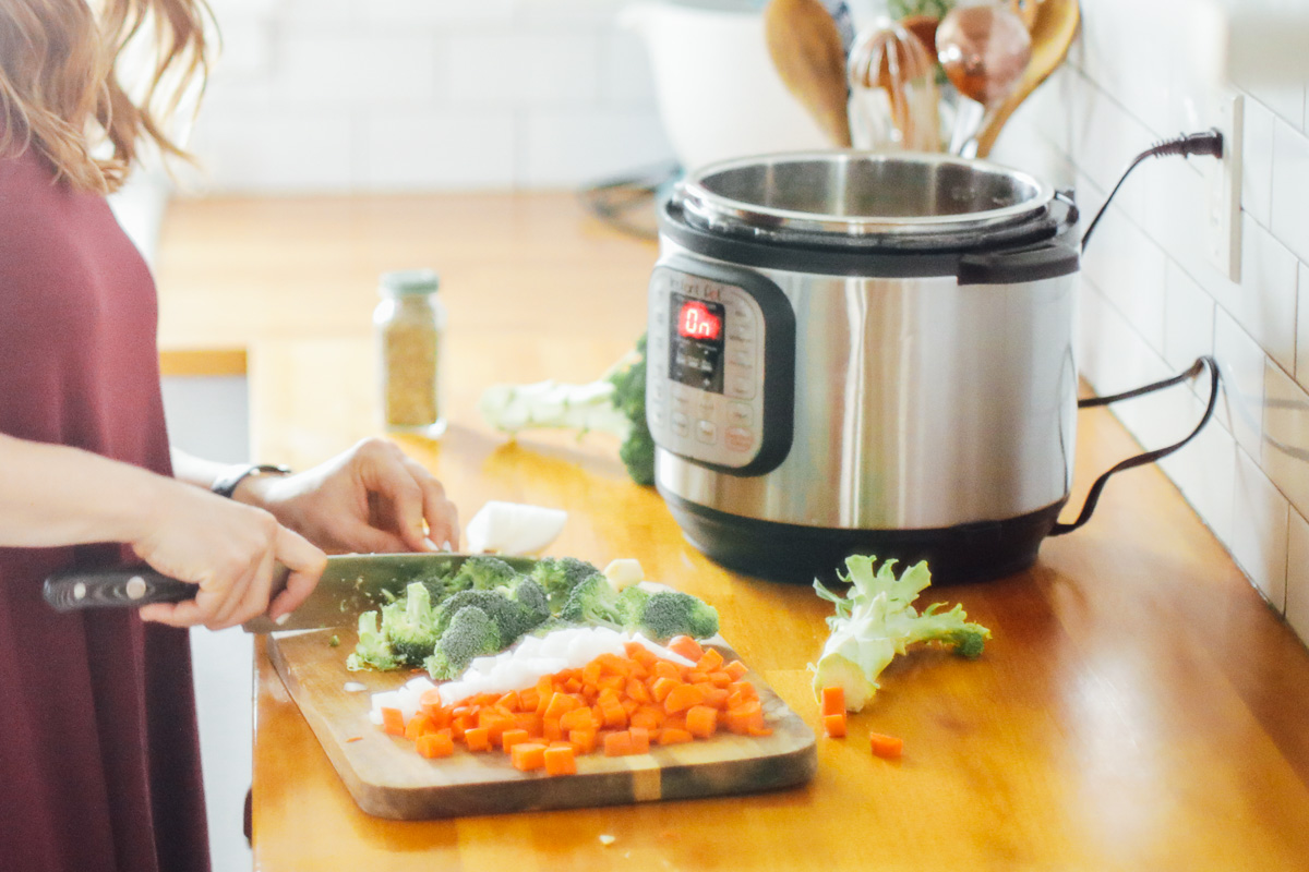 Cutting the broccoli, carrots, and onions with an Instant Pot in the background.