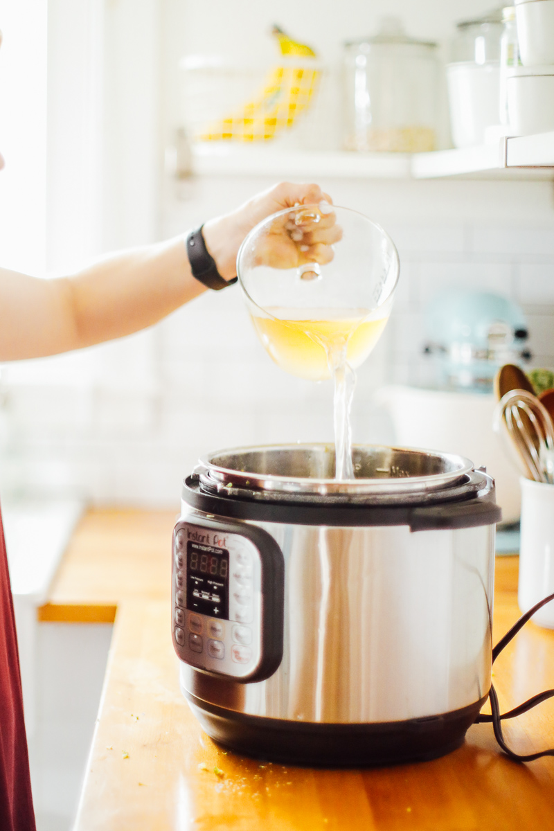 Pouring chicken broth into a hot Instant Pot.