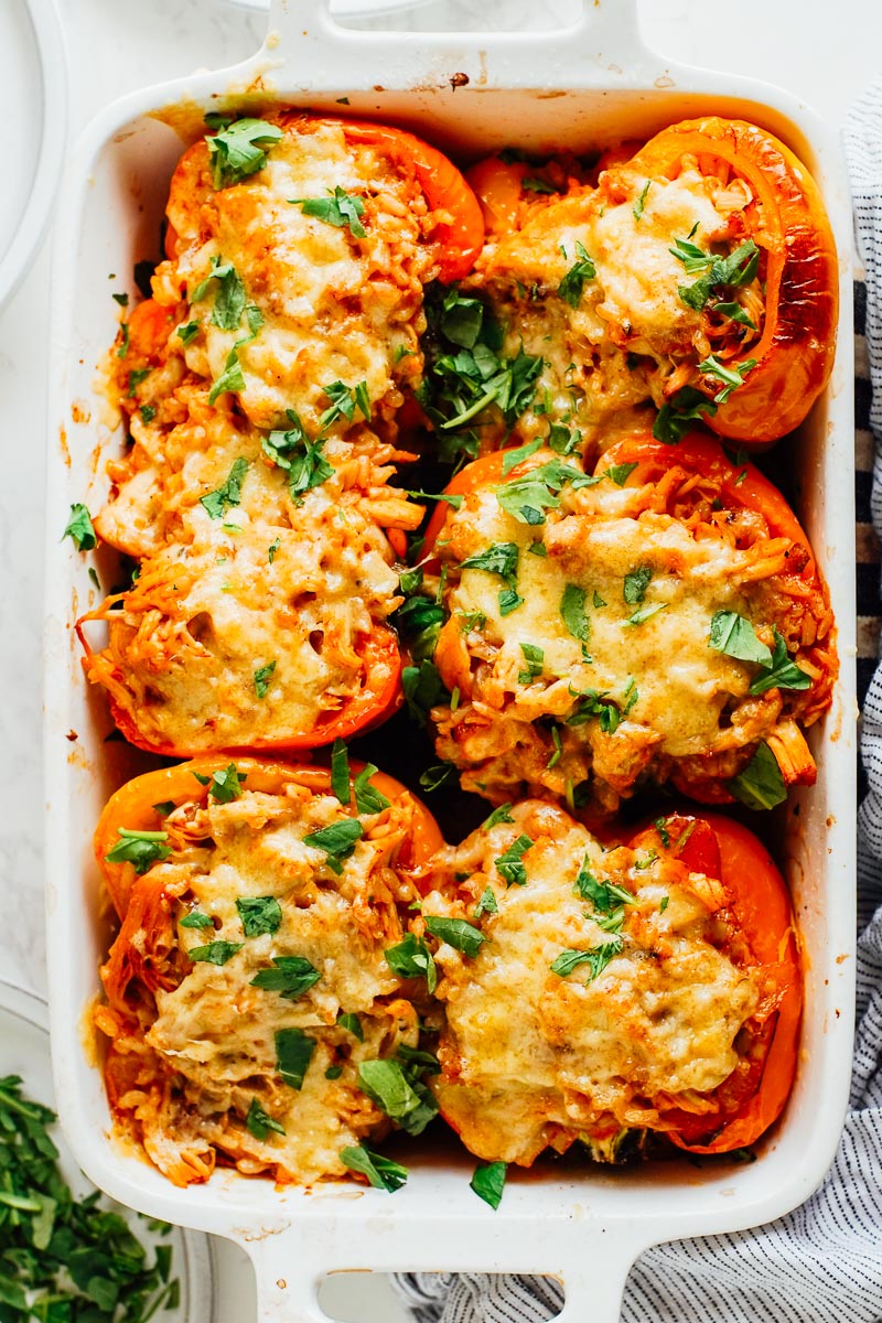 Cooked stuffed bell peppers in a casserole dish with melted cheese on top.