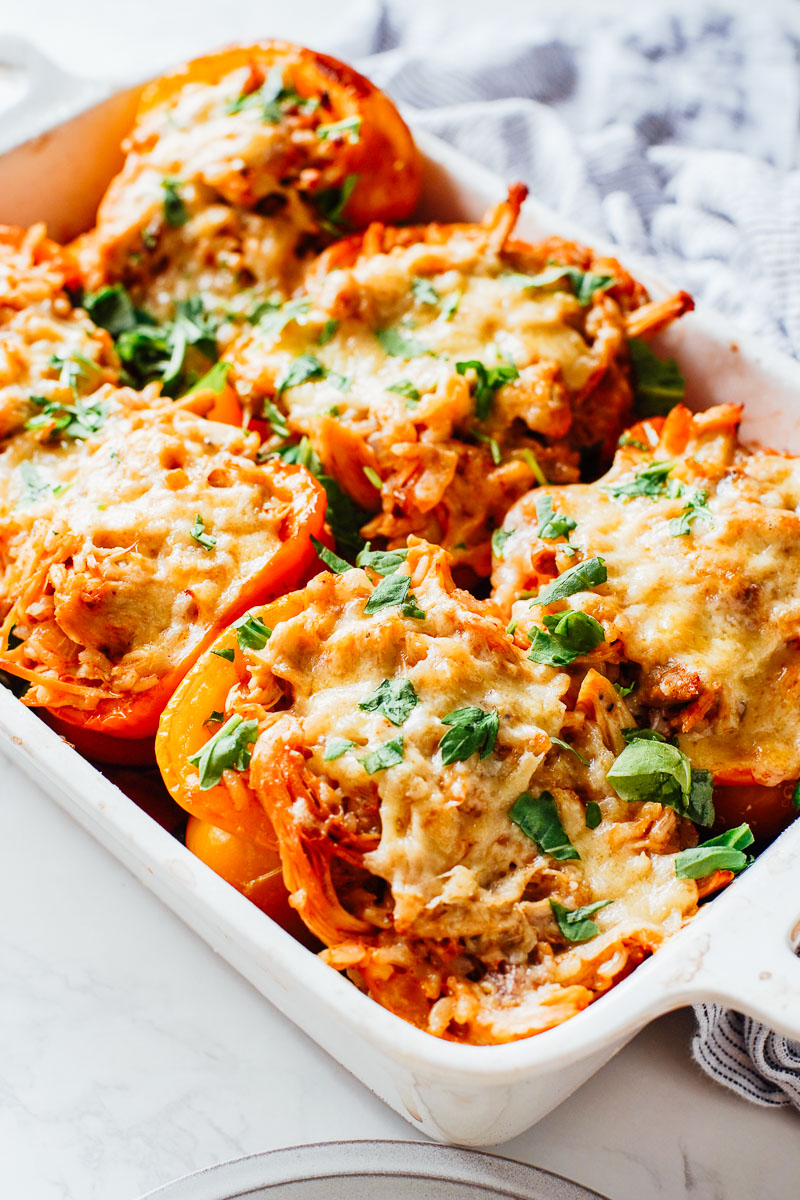 Stuffed peppers with cheese on top in a casserole dish.