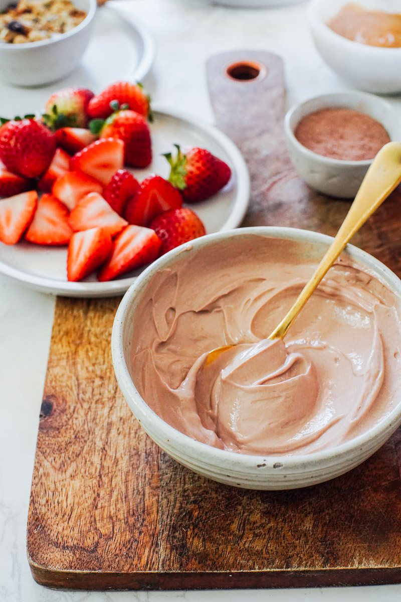 Chocolate yogurt in a bowl with strawberries in the background.