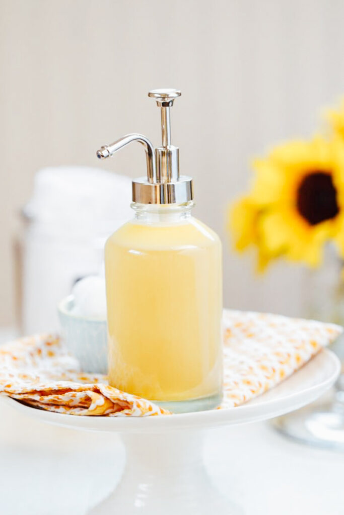 Honey face wash in a glass soap dispenser.