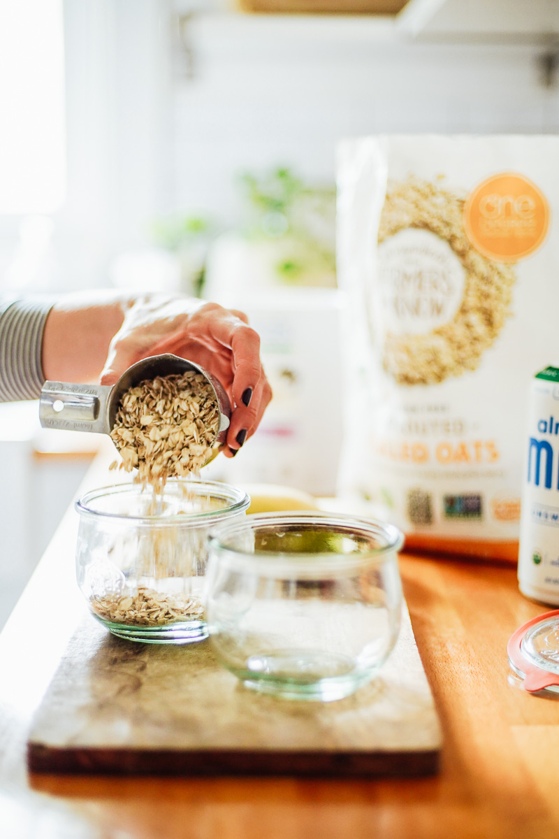 Pouring rolled oats into a glass jar.