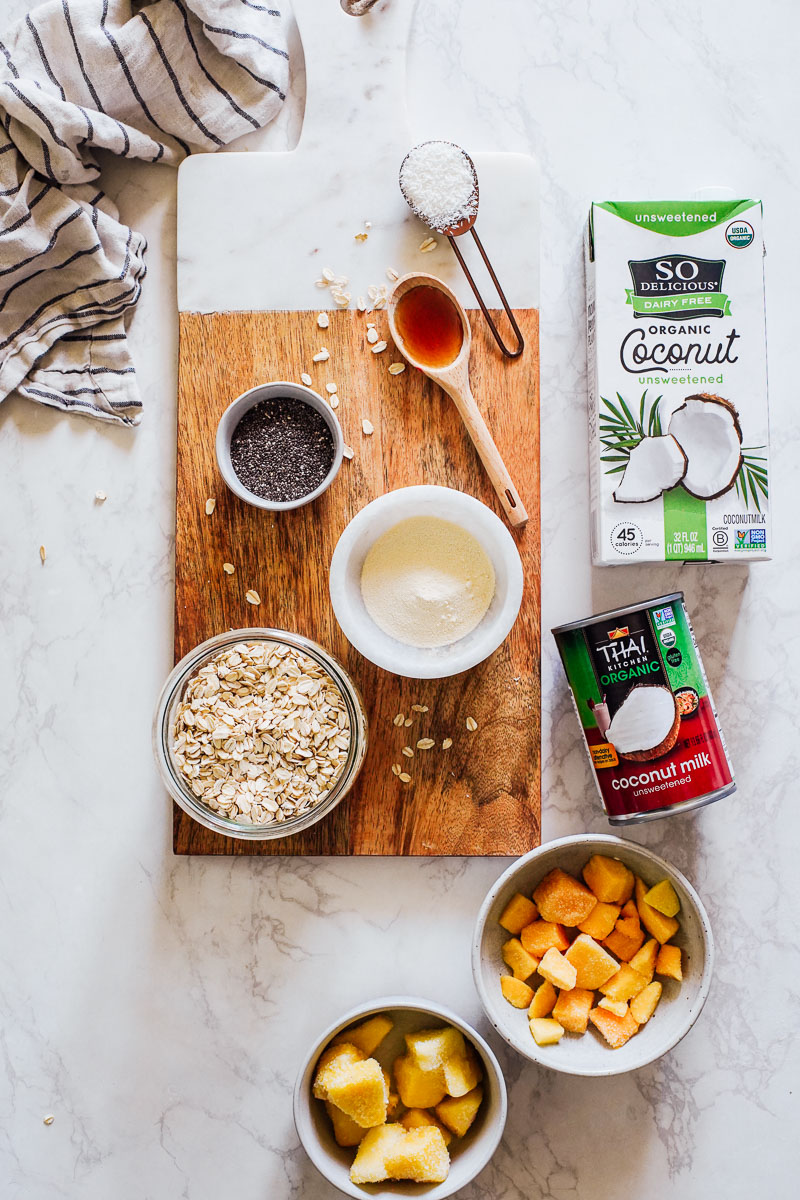 Overnight oat ingredients: coconut milk (canned or in a carton), protein powder, chia seeds, tropical fruit, maple syrup, and shredded coconut. 